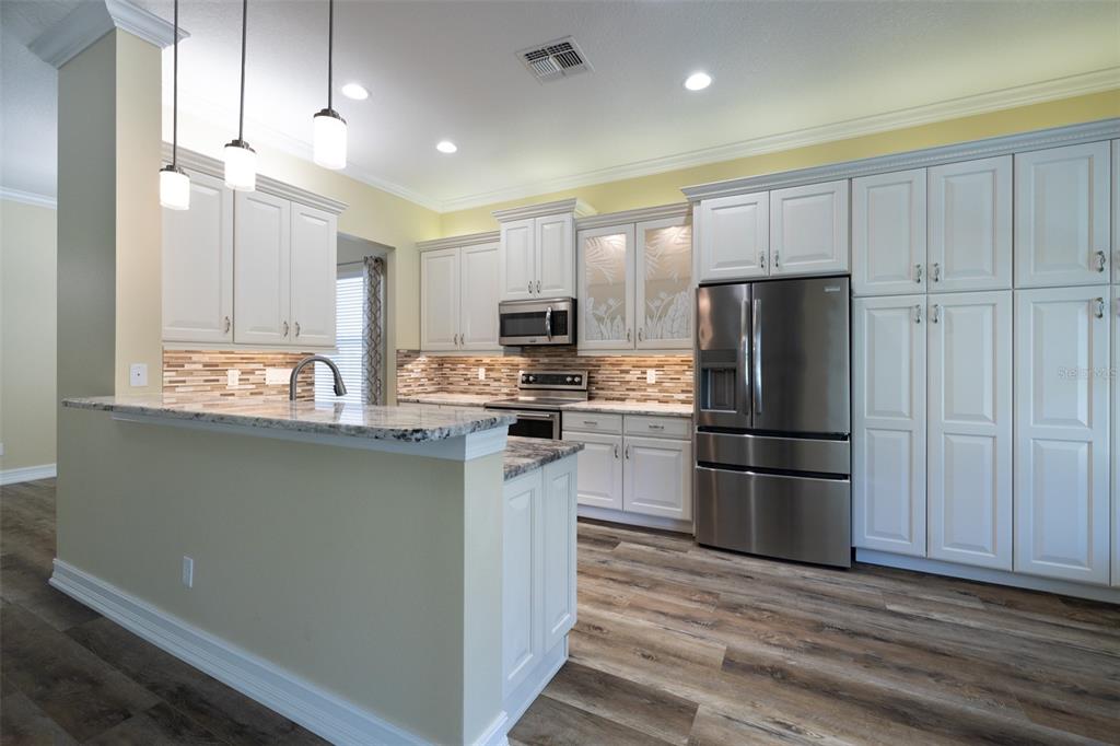 16122 Cedar Key Drive Wimauma, FL 33598 - Photo 24 of 98 a kitchen with kitchen island a refrigerator sink and cabinets