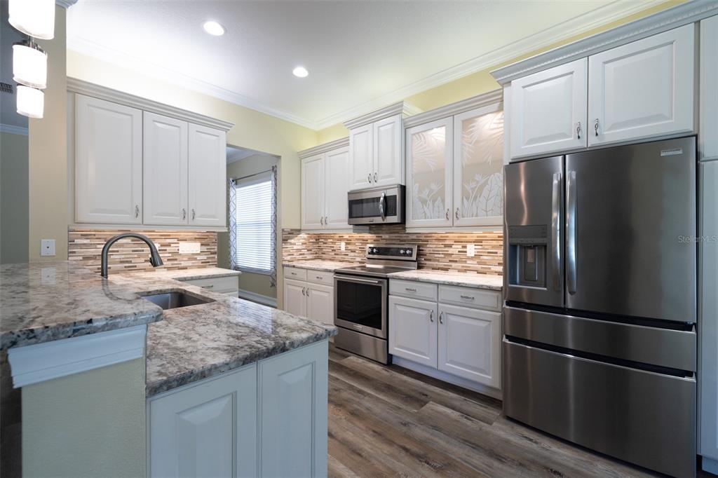 16122 Cedar Key Drive Wimauma, FL 33598 - Photo 25 of 98 a kitchen with granite countertop stainless steel appliances and wooden cabinets