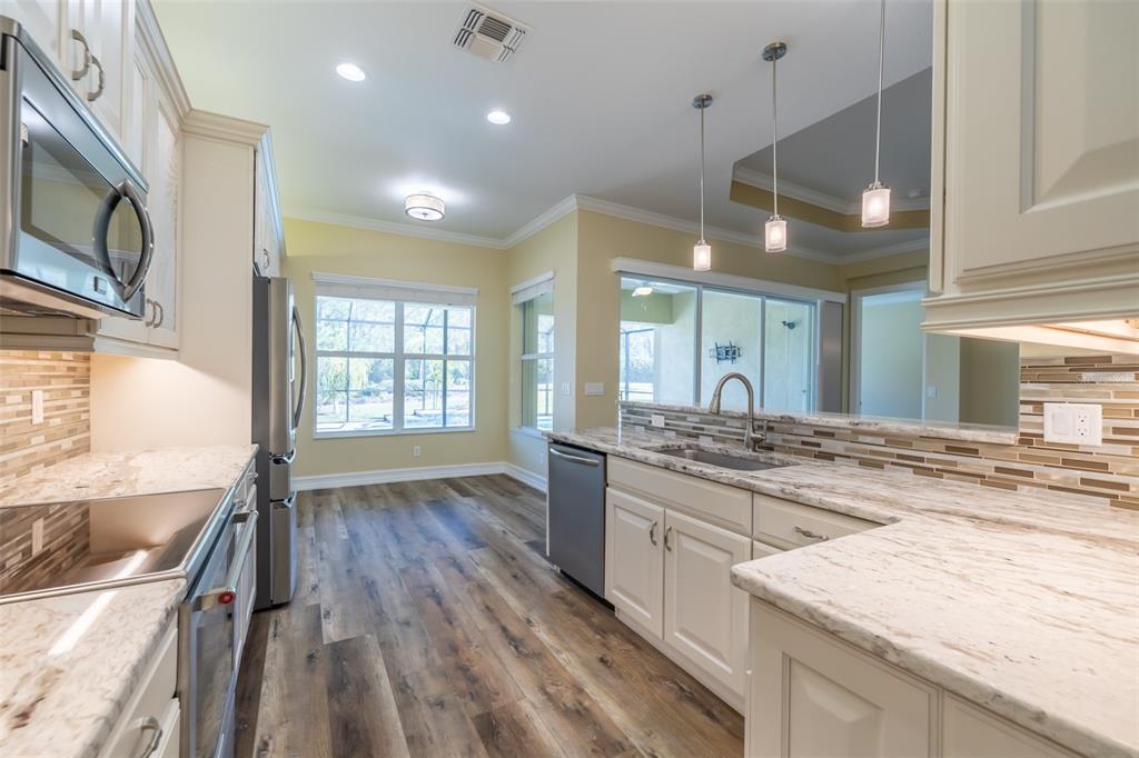 16122 Cedar Key Drive Wimauma, FL 33598 - Photo 27 of 98 a large kitchen with stainless steel appliances granite countertop a stove and a wooden floors