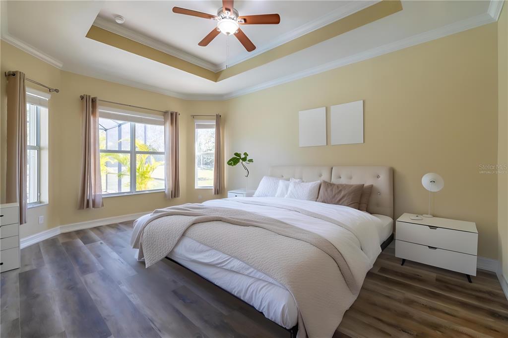 16122 Cedar Key Drive Wimauma, FL 33598 - Photo 45 of 98 a bedroom with a large bed and a chandelier