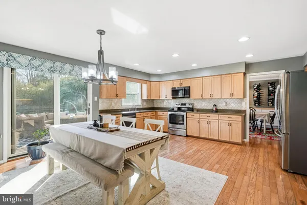 a large open kitchen with granite countertop a stove top oven a sink a dining table and chairs with wooden floor