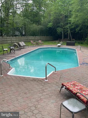 a view of swimming pool with large trees and lawn chairs