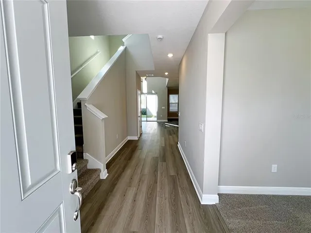 a view of a hallway with wooden floor and staircase