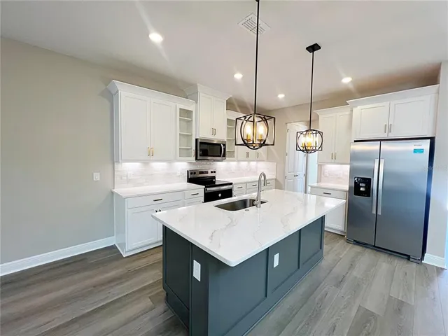 a kitchen with a sink a stove a refrigerator and wooden floor