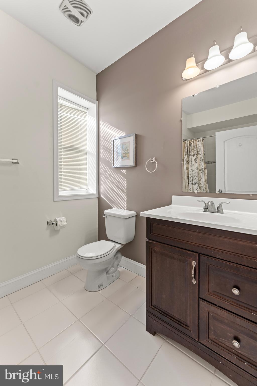 3616 Reisterstown Road Baltimore, MD 21215 - Photo 21 of 34 a bathroom with a toilet a sink a mirror a window and vanity