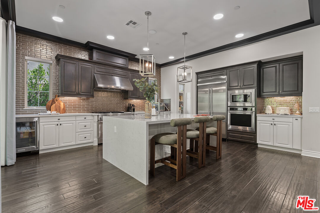55 Suede Irvine, CA 92602 - Photo 16 of 59 a kitchen with stainless steel appliances kitchen island granite countertop a stove a sink a refrigerator and white cabinets with wooden floor