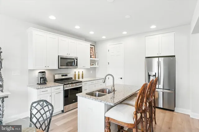 a kitchen with stainless steel appliances granite countertop a refrigerator a stove a sink a dining table and chairs