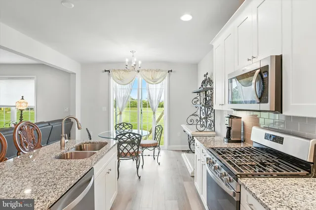 a kitchen with granite countertop a stove a sink a dining table and chairs