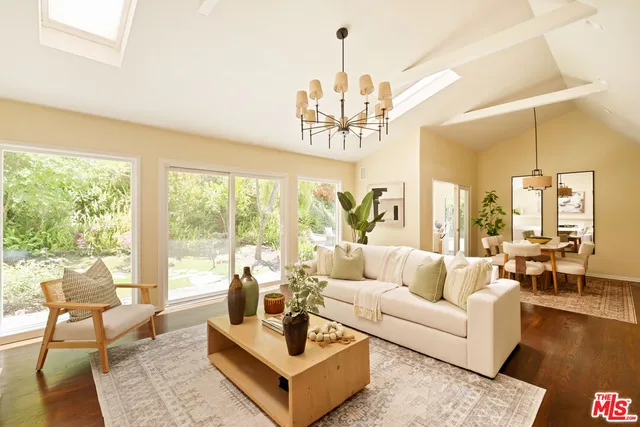 a living room with couch a table and a large window with garden view