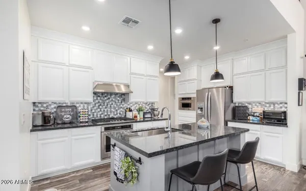 a kitchen with stainless steel appliances kitchen island granite countertop a sink and refrigerator