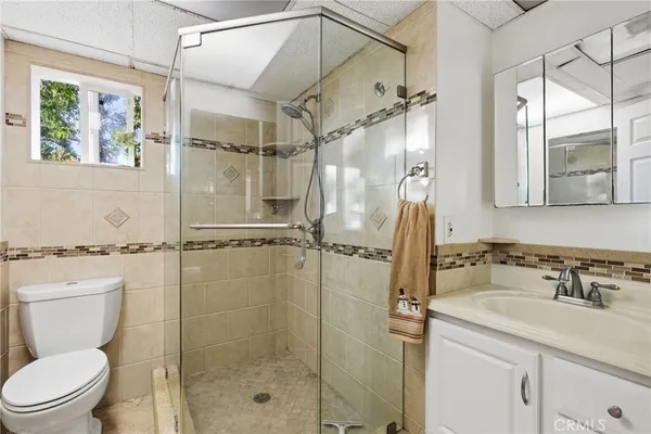 a bathroom with a shower sink vanity mirror and toilet