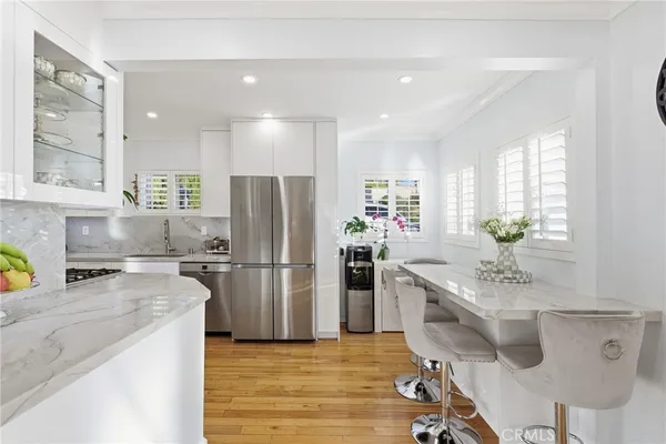 a kitchen with stainless steel appliances granite countertop a refrigerator a stove a sink a dining table and chairs