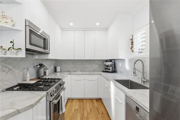a kitchen with stainless steel appliances granite countertop white cabinets a stove top oven a sink and dishwasher