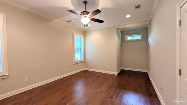 an empty room with wooden floor chandelier fan and windows