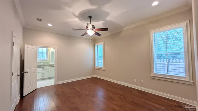 an empty room with wooden floor chandelier fan and windows
