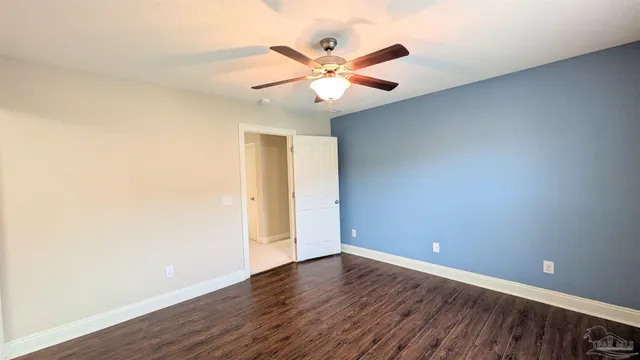 an empty room with wooden floor and fan