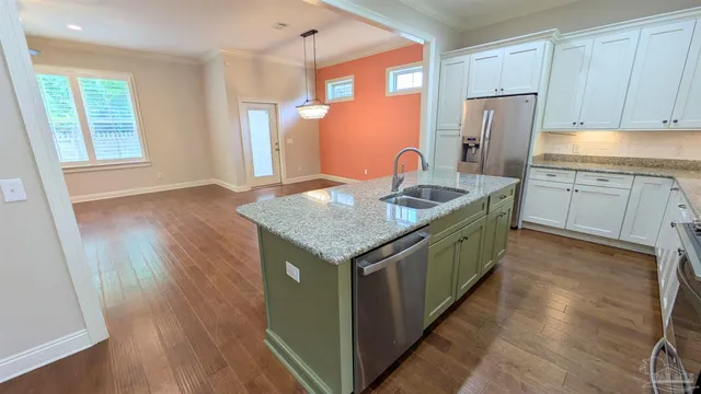 a kitchen with stainless steel appliances granite countertop a kitchen island a stove a refrigerator a sink and dishwasher with wooden floor