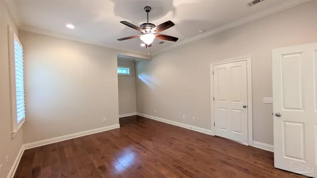 an empty room with wooden floor chandelier fan and closet area