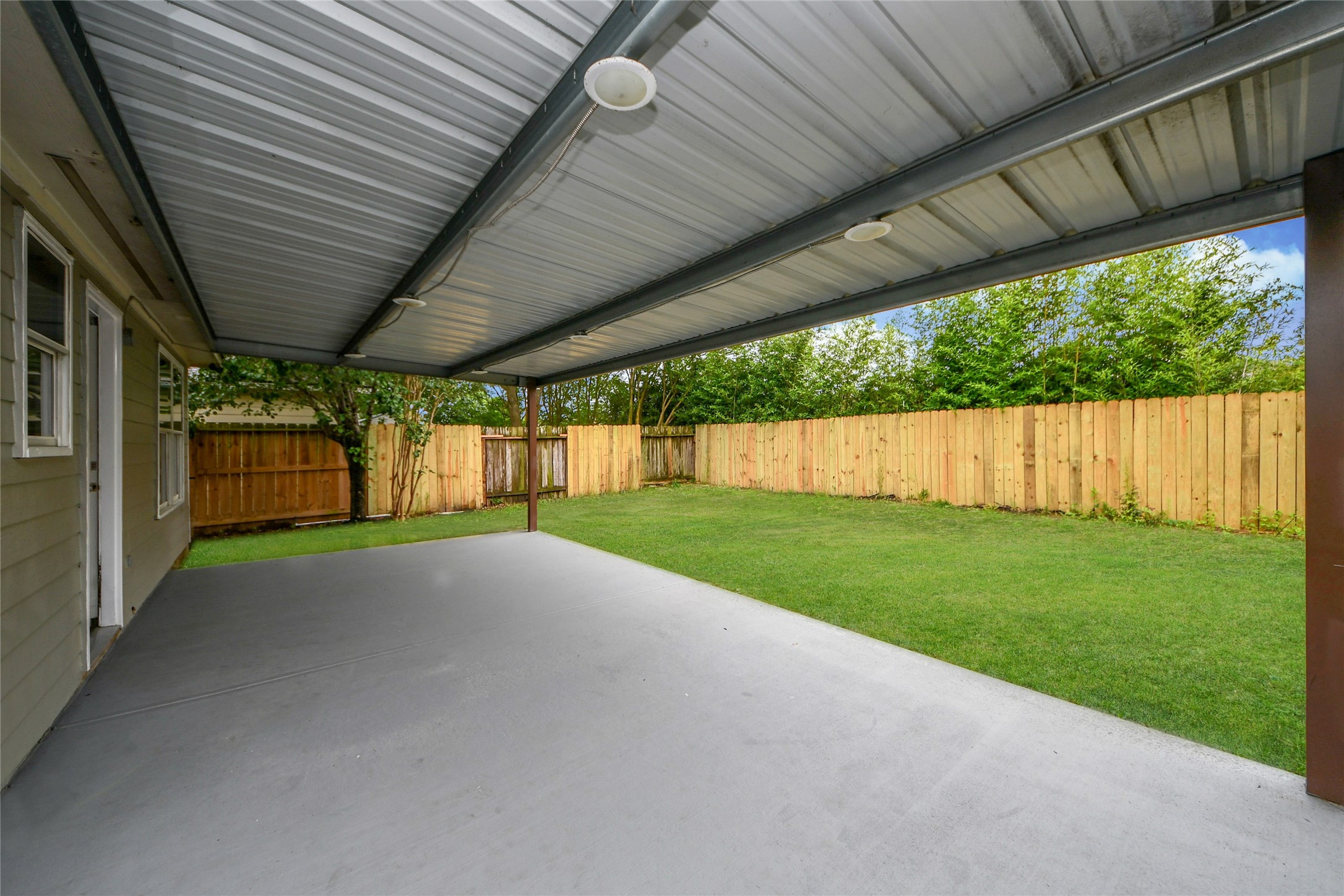 24019 Kingbriar Drive Spring, TX 77373 - Photo 37 of 41 Relax under this generous covered patio, featuring a concrete pad and overhead lighting, which transitions seamlessly to the fully fenced, grassy backyard for private enjoyment.