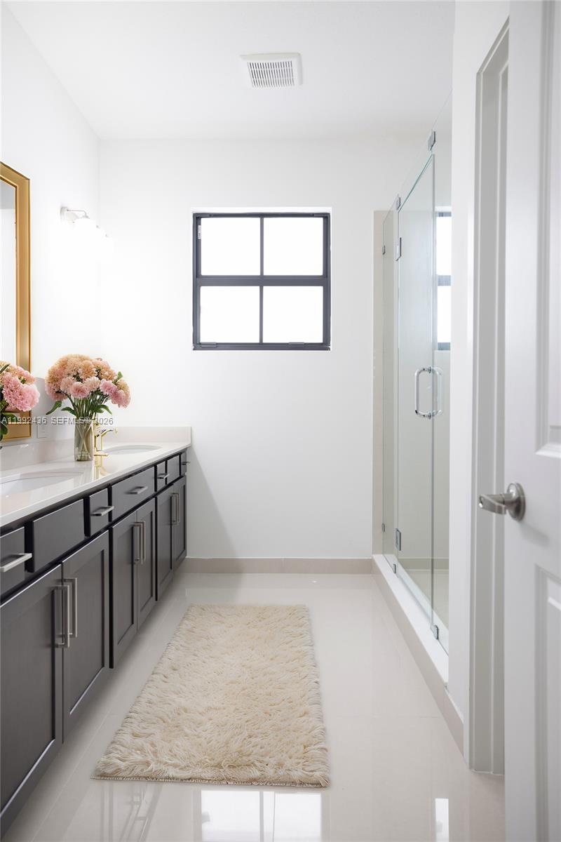1841 Southwest 145th Avenue, Unit 1841 Miami, FL 33175 - Photo 18 of 23 a bathroom with a double vanity sink a mirror and a shower