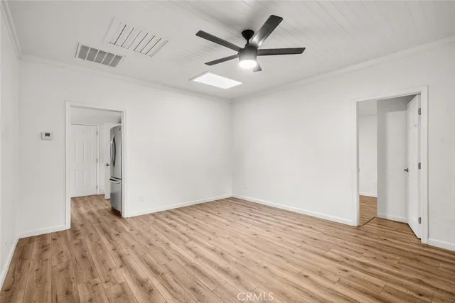 an empty room with wooden floor and a ceiling fan
