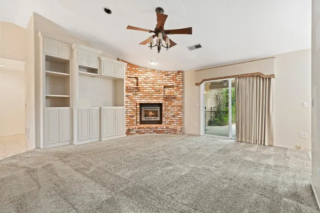 a view of an empty room with a fireplace and a window