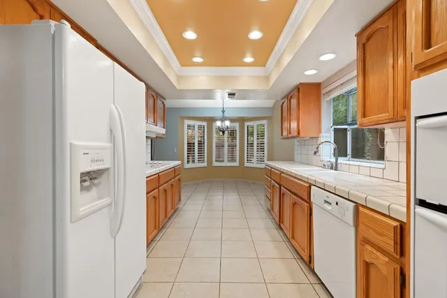 a large white kitchen with granite countertop a sink and dishwasher with a large window
