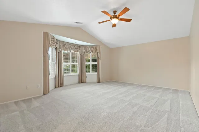 an empty room with windows and ceiling fan
