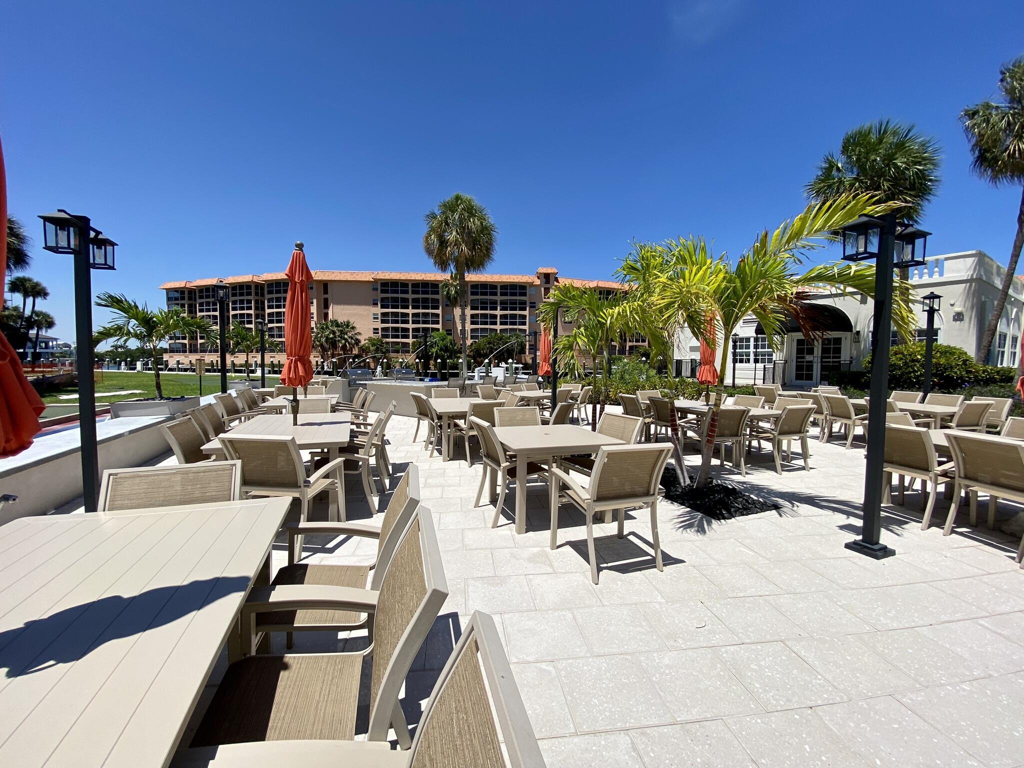 2871 North Ocean Boulevard, Unit V443 Boca Raton, FL 33431 - Photo 26 of 49 a view of a patio with dining table and chairs under an umbrella with palm trees