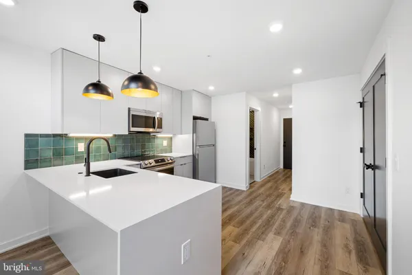 a kitchen with kitchen island a sink stainless steel appliances and a chandelier