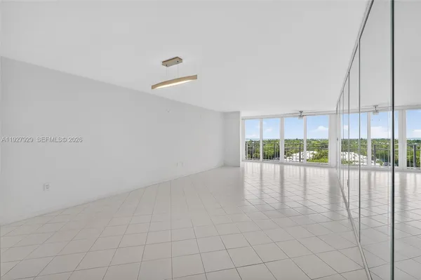 a view of an empty room with wooden floor and windows