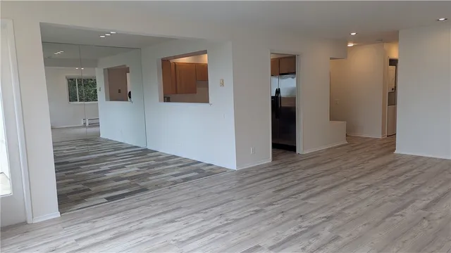 a view of a hallway with wooden floor and a bathroom