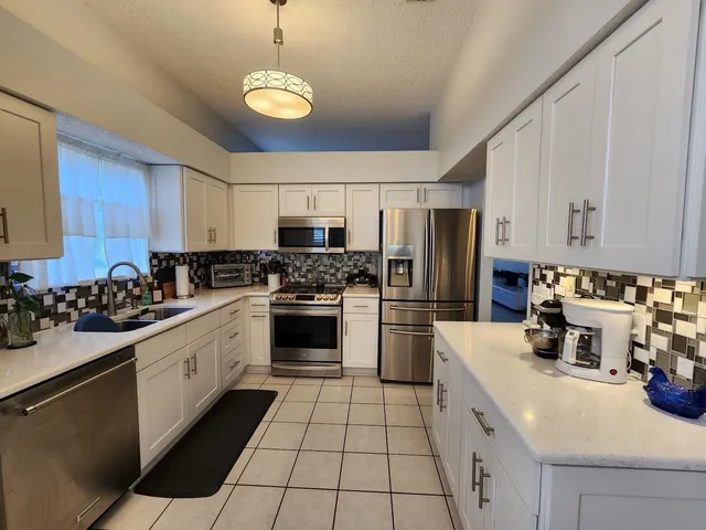 a kitchen with stainless steel appliances a sink a stove a refrigerator cabinets and a dining table