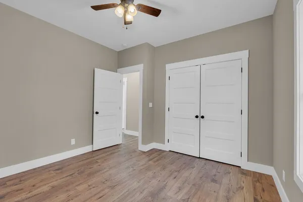 an empty room with wooden floor closet and chandelier fan