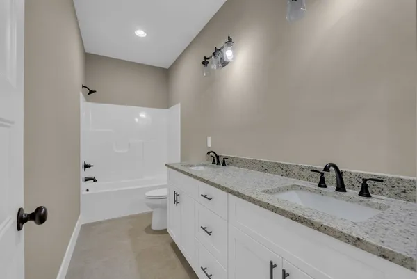 a bathroom with a granite countertop sink a toilet and shower