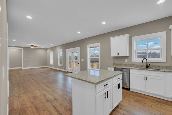 a bathroom with a granite countertop sink a toilet a large mirror and a window