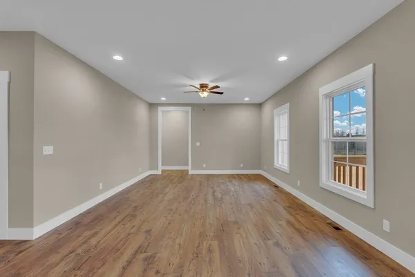 a view of an empty room with wooden floor and a window