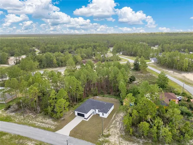 an aerial view of residential house with outdoor space and trees all around