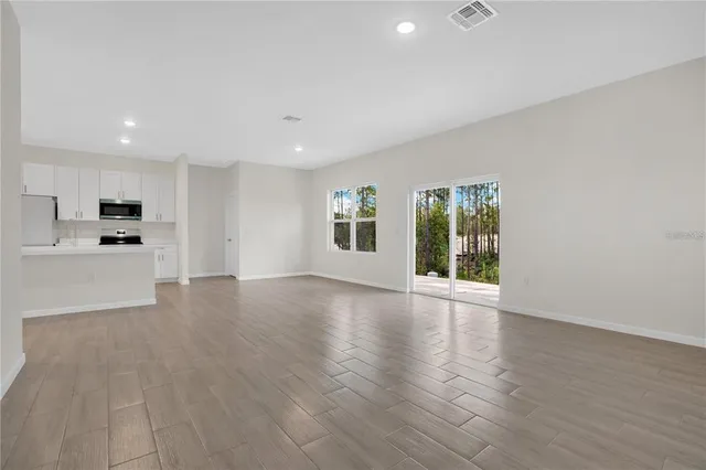 a view of an empty room with window and wooden floor