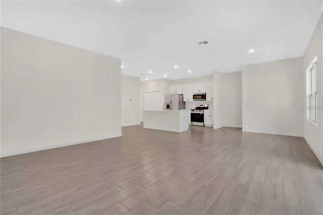 a view of a big room with wooden floor and windows
