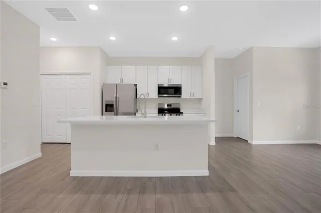 a living room with stainless steel appliances a refrigerator sink and microwave