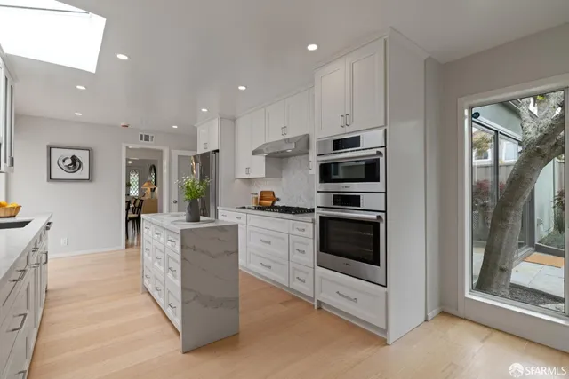 a large kitchen with stainless steel appliances kitchen island granite countertop a refrigerator and a stove top oven