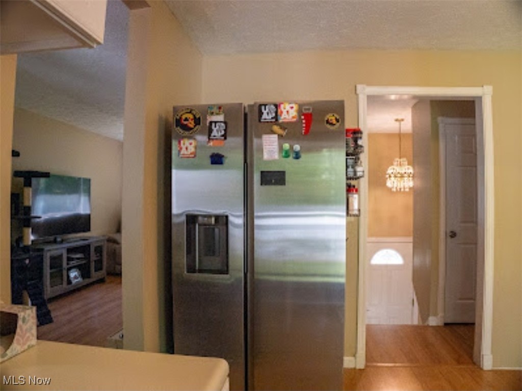 1770 Meadows Road Madison, OH 44057 - Photo 4 of 22 Kitchen with stainless steel fridge, a chandelier, wood finished floors, and a textured ceiling