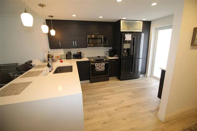 a kitchen with stainless steel appliances kitchen island granite countertop a refrigerator a stove a sink a oven and a refrigerator