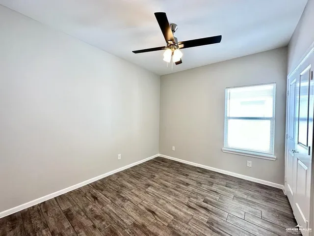 an empty room with a window and ceiling fan