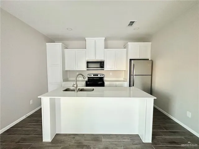 a kitchen with kitchen island a white counter top space cabinets and stainless steel appliances