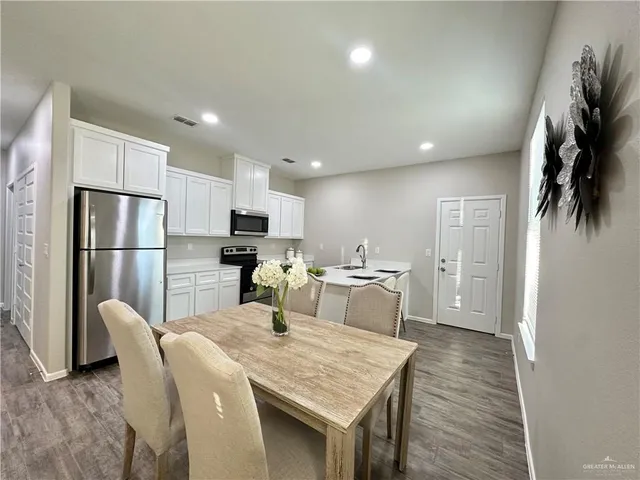 a kitchen with stainless steel appliances granite countertop a refrigerator a stove a sink a dining table and chairs