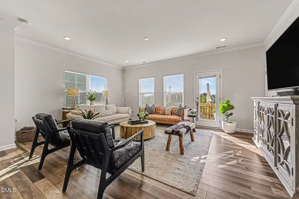 a kitchen with stainless steel appliances a refrigerator a stove a sink dishwasher a dining table and chairs with wooden floor