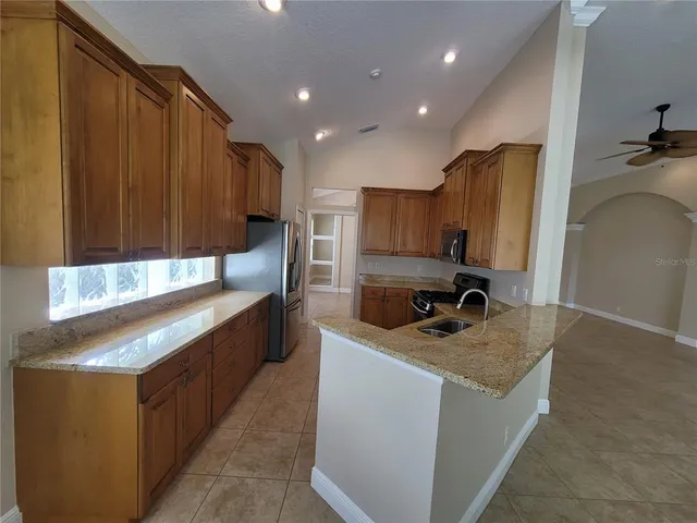 a kitchen with granite countertop a sink a stove and cabinets