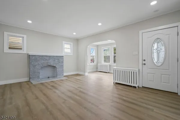 an empty room with wooden floor fireplace and windows